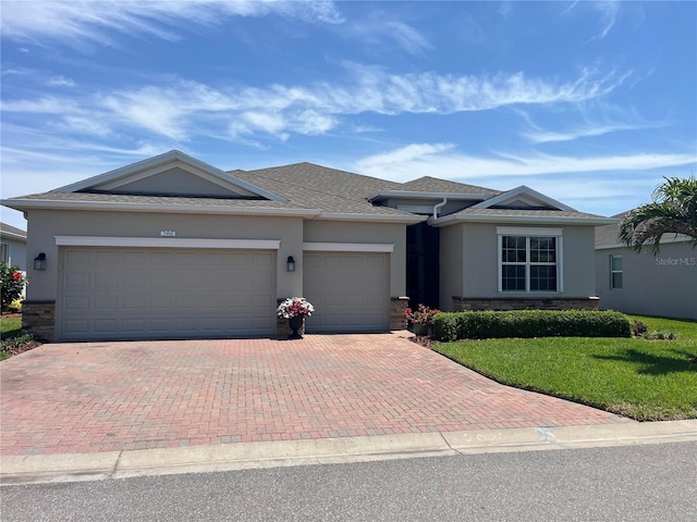view of front of house with roof with shingles, a front yard, decorative driveway, an attached garage, and stucco siding