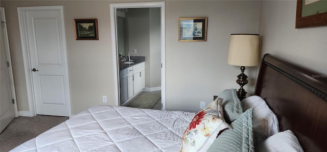 carpeted bedroom featuring a sink, baseboards, and ensuite bath