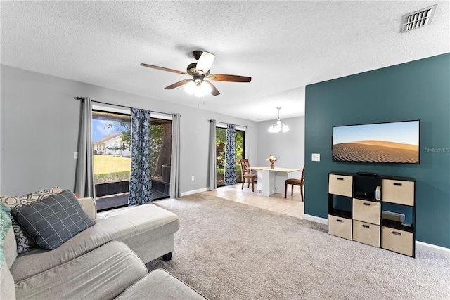 living room featuring ceiling fan, carpet floors, baseboards, a textured ceiling, and a chandelier