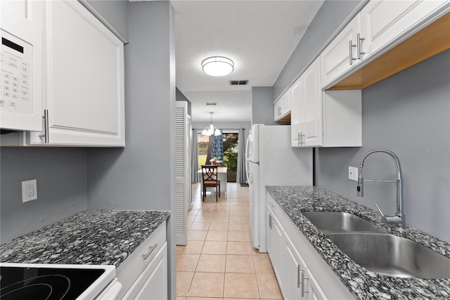 kitchen featuring a sink, light tile patterned floors, white appliances, white cabinetry, and a textured ceiling
