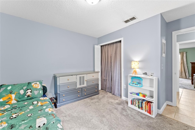 tiled bedroom featuring carpet, a textured ceiling, baseboards, and a closet