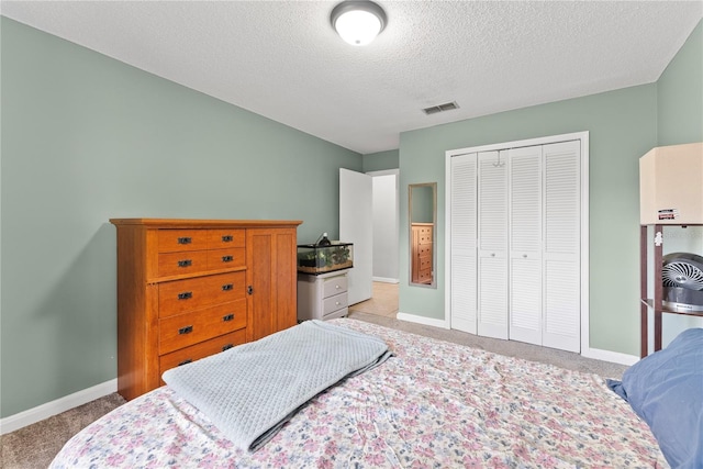 carpeted bedroom with a textured ceiling, a closet, and baseboards