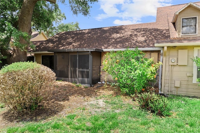 back of property with roof with shingles and a sunroom