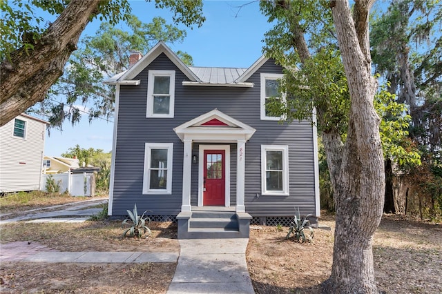 traditional home featuring a chimney and metal roof
