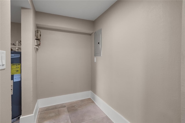 clothes washing area with baseboards, water heater, tile patterned flooring, and electric panel