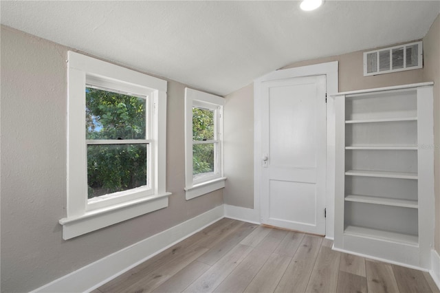 interior space featuring visible vents, a closet, lofted ceiling, wood finished floors, and baseboards