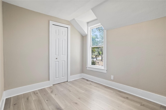 additional living space featuring baseboards, lofted ceiling, and light wood finished floors