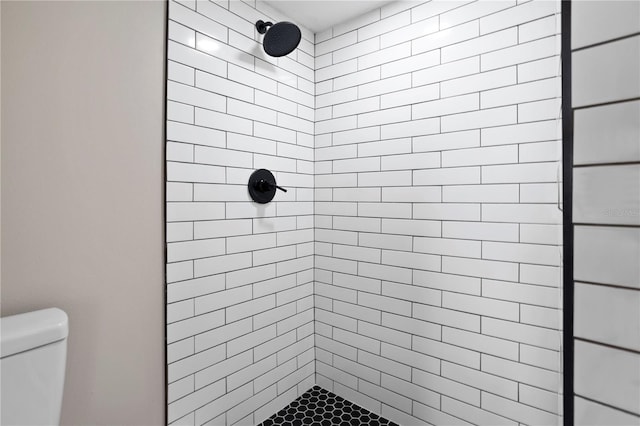 bathroom with a tile shower and toilet