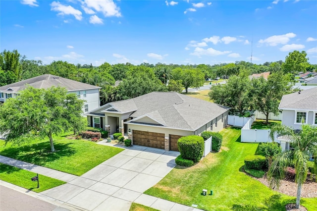 view of front facade featuring driveway, fence, a front lawn, an attached garage, and a shingled roof