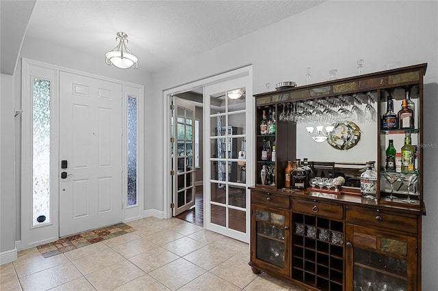 foyer entrance with light tile patterned floors, baseboards, and a bar