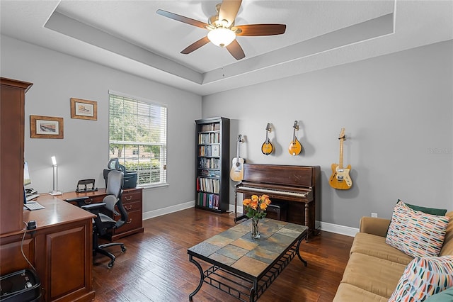 office space featuring baseboards, a ceiling fan, wood finished floors, and a tray ceiling