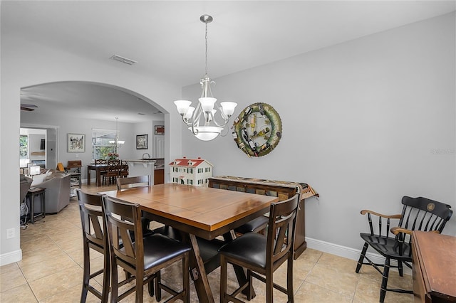dining area featuring arched walkways, a notable chandelier, light tile patterned flooring, and visible vents