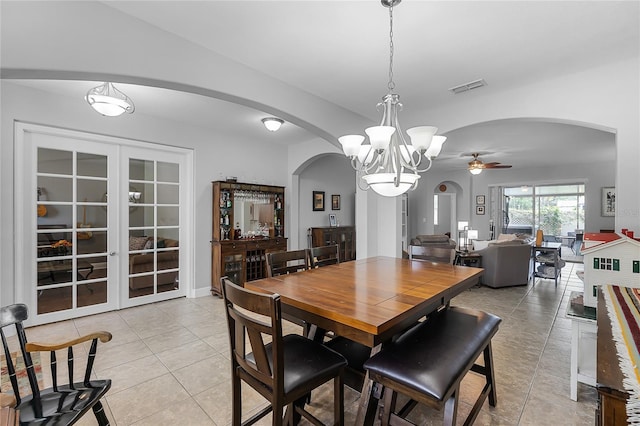 dining room with arched walkways, visible vents, light tile patterned floors, and ceiling fan with notable chandelier