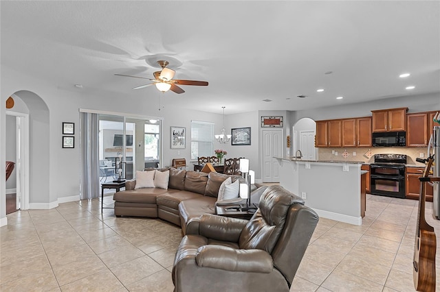 living area with arched walkways, baseboards, ceiling fan with notable chandelier, recessed lighting, and light tile patterned flooring