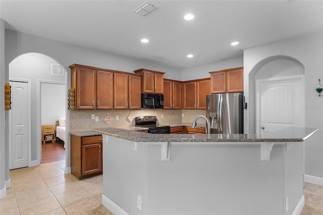 kitchen with stainless steel appliances, arched walkways, visible vents, and brown cabinetry