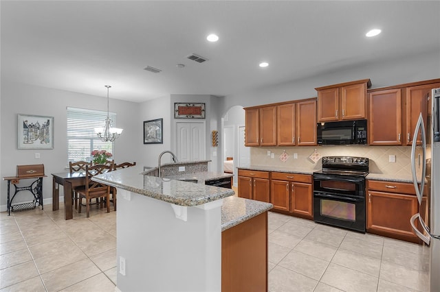 kitchen featuring decorative backsplash, arched walkways, brown cabinetry, and black appliances