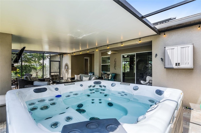 exterior space featuring glass enclosure, ceiling fan, and a hot tub