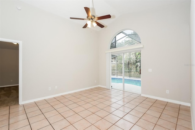 empty room featuring light tile patterned floors, high vaulted ceiling, ceiling fan, and baseboards