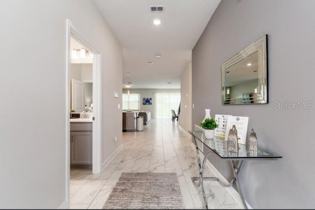 corridor featuring baseboards, marble finish floor, and visible vents