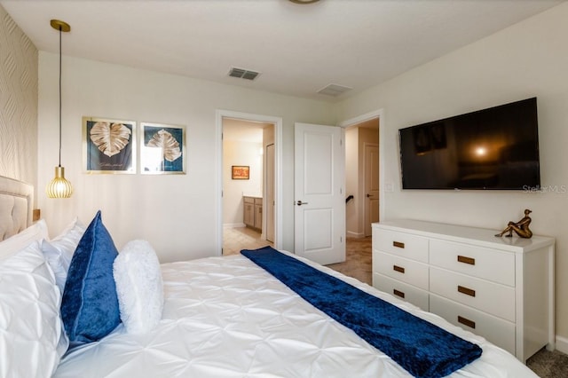 bedroom with ensuite bathroom, light carpet, baseboards, and visible vents