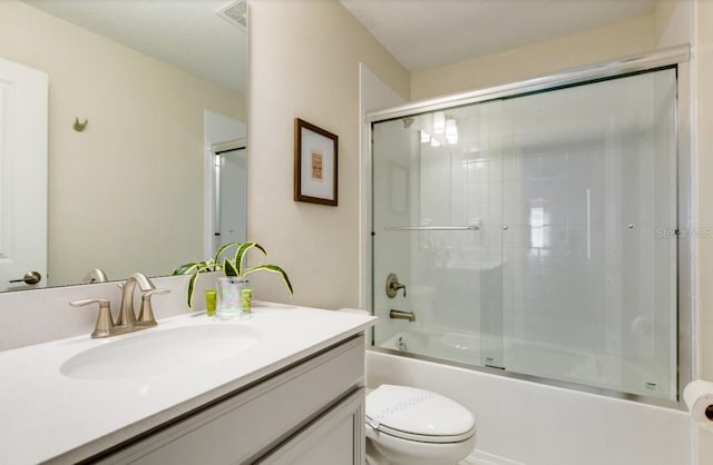 full bath with toilet, vanity, visible vents, and bath / shower combo with glass door