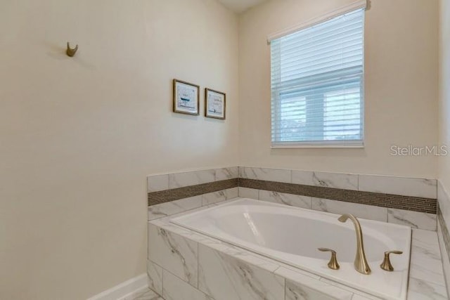 full bathroom featuring baseboards and a bath