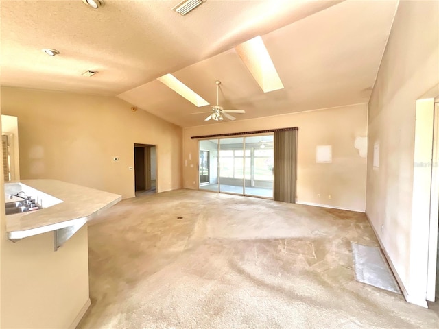 6042 Wade St, Leesburg, FL 34748 - unfurnished living room featuring visible vents, light carpet, lofted ceiling with skylight, and ceiling fan