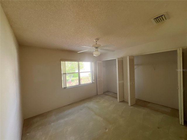 6042 Wade St, Leesburg, FL 34748 - unfurnished bedroom featuring light colored carpet, multiple closets, visible vents, a ceiling fan, and a textured ceiling