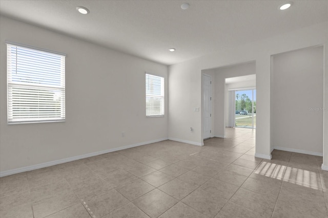 empty room with light tile patterned floors, recessed lighting, and baseboards