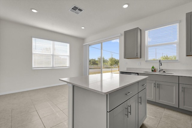 kitchen with gray cabinets, a wealth of natural light, a sink, visible vents, and light tile patterned flooring