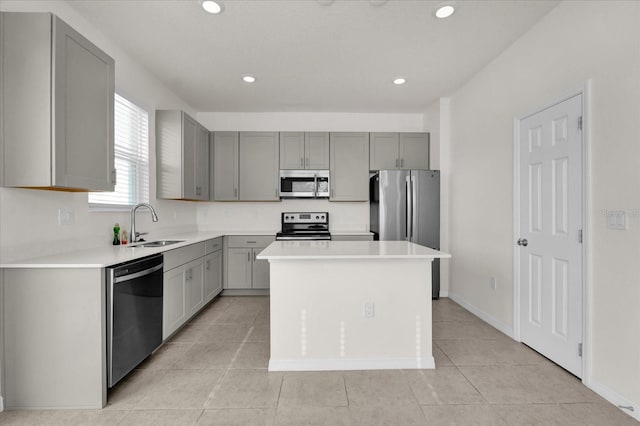 kitchen with gray cabinetry, a center island, stainless steel appliances, and a sink