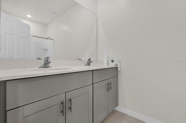 full bathroom with tile patterned floors, baseboards, double vanity, and a sink