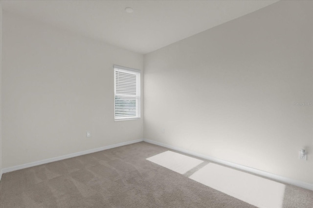 spare room featuring baseboards and light carpet
