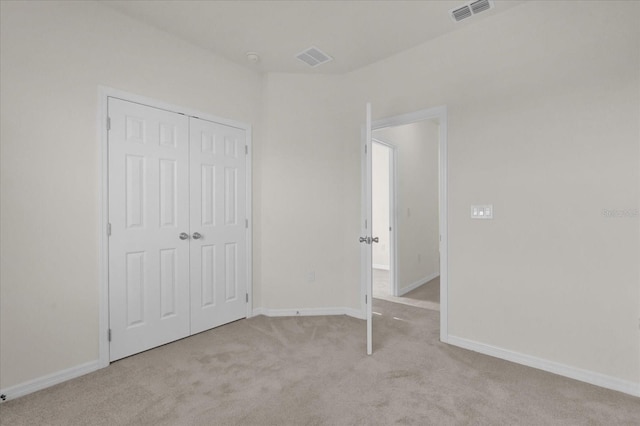 unfurnished bedroom featuring visible vents, baseboards, carpet flooring, and a closet