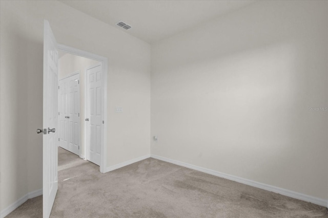 unfurnished room featuring light colored carpet, visible vents, and baseboards