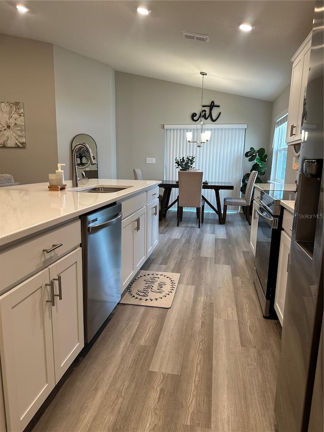 2000 Golden Beak Dr, Eagle Lake, FL 33839 - kitchen with visible vents, vaulted ceiling, wood finished floors, light countertops, and stainless steel appliances