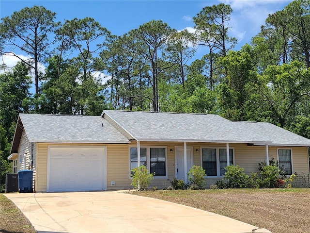 ranch-style home featuring an attached garage, concrete driveway, covered porch, and a shingled roof