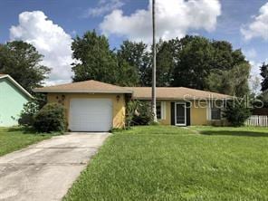 ranch-style home featuring concrete driveway, an attached garage, and a front lawn