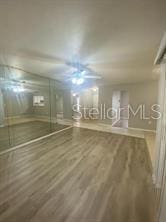 spare room featuring wood finished floors, ceiling fan, and baseboards