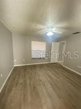 additional living space featuring wood finished floors, a ceiling fan, and baseboards