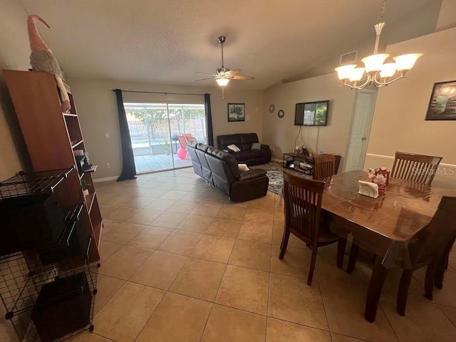 dining space featuring light tile patterned floors, visible vents, baseboards, lofted ceiling, and ceiling fan with notable chandelier