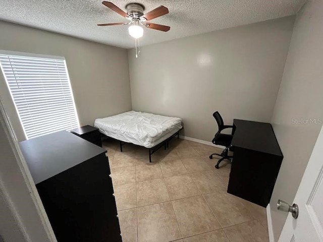 bedroom with light tile patterned floors, a ceiling fan, and a textured ceiling