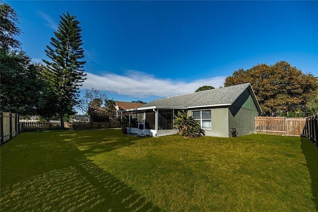 back of property featuring a fenced backyard, a sunroom, and a lawn