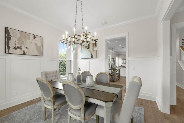 dining area featuring a chandelier, wood finished floors, and a decorative wall