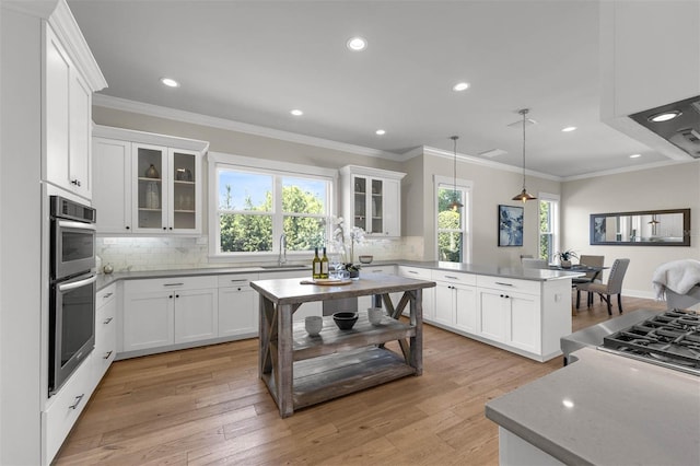 kitchen featuring backsplash, a sink, a peninsula, and white cabinetry