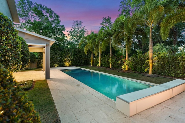 pool at dusk featuring a patio and an outdoor pool