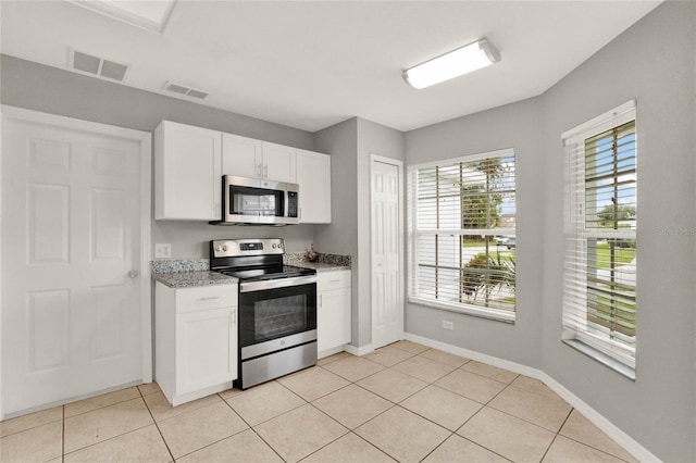 4347 Creekside Blvd, Kissimmee, FL 34746 - kitchen with appliances with stainless steel finishes, light tile patterned floors, white cabinets, baseboards, and light stone counters