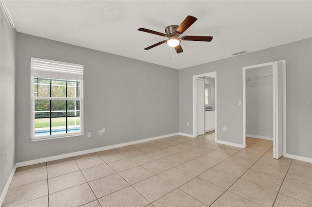 4347 Creekside Blvd, Kissimmee, FL 34746 - unfurnished bedroom featuring light tile patterned floors, baseboards, ceiling fan, a closet, and a textured ceiling