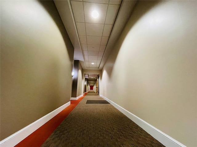 corridor with attic access, a drop ceiling, recessed lighting, and baseboards