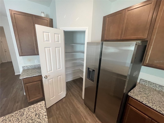 kitchen with stainless steel fridge, dark wood-type flooring, and light stone counters
